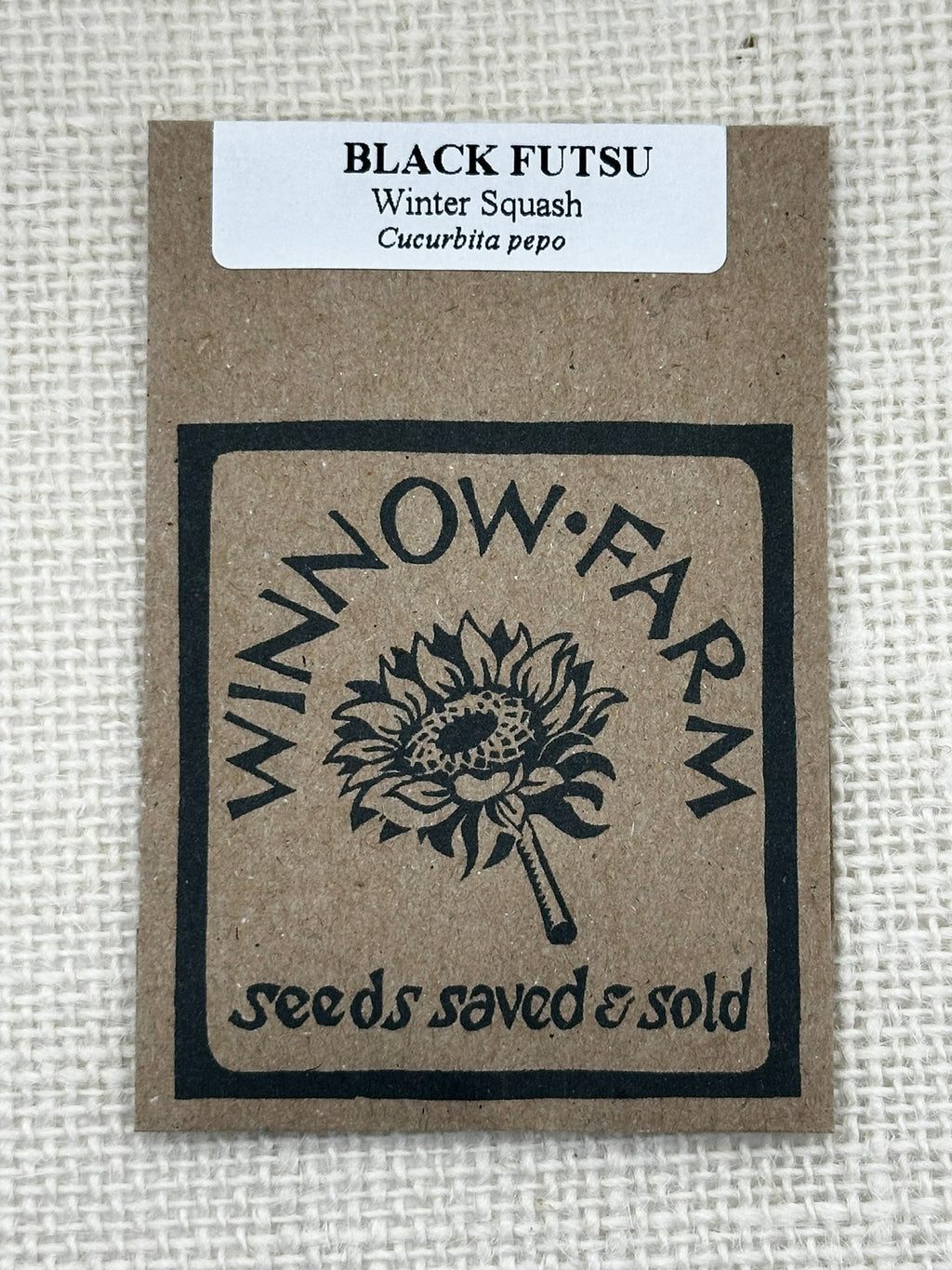 Seed packet for Black Futsu winter squash from Winnow Farm on a textured beige background