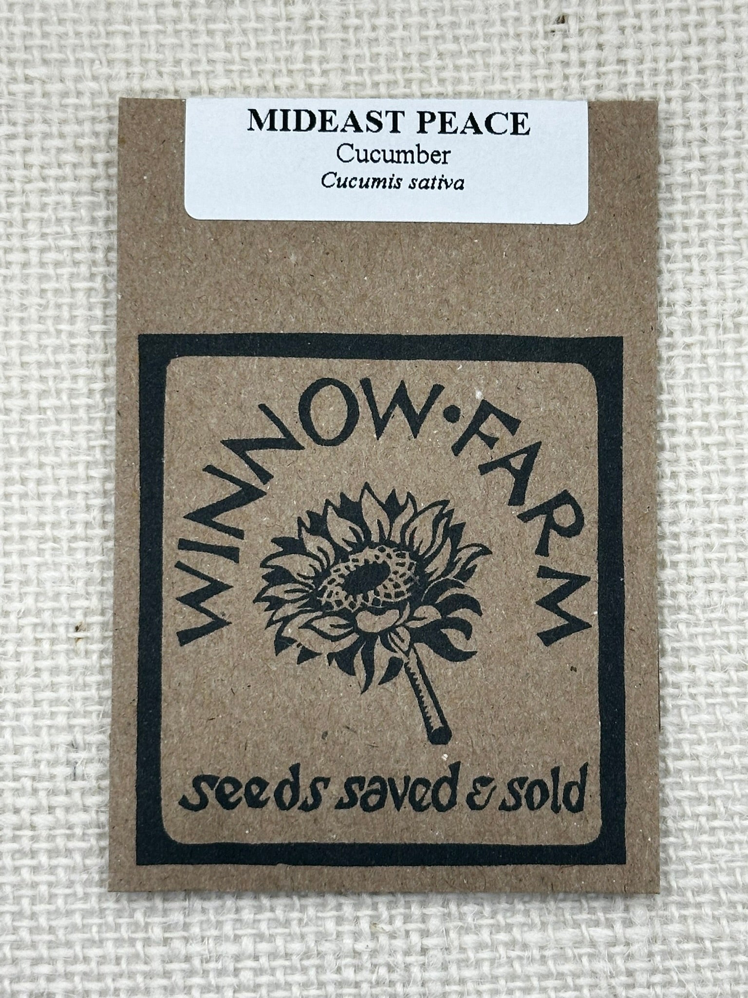 Seed packet from Winnow Farm with 'Mideast Peace' cucumber variety on a textured beige background