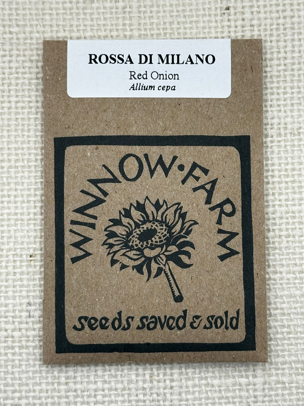 Seed packet for Rossa di Milano red onion from Winnow Farm on a textured beige background